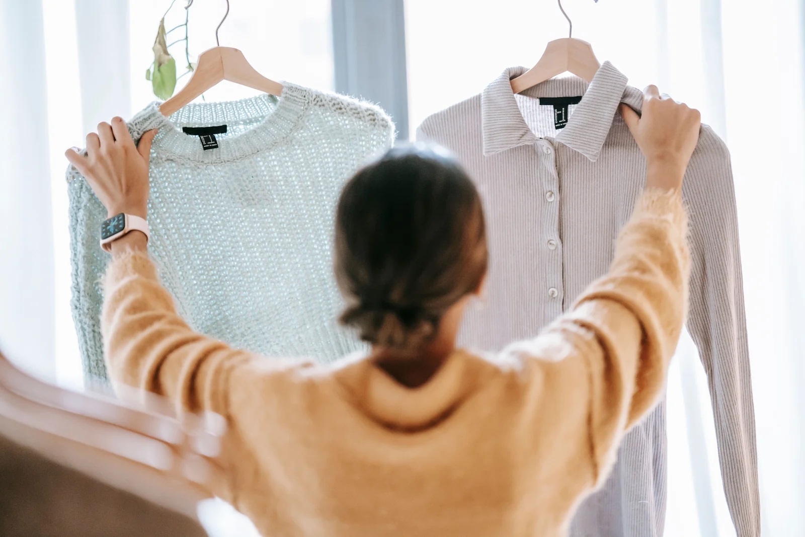 A woman considering two clothing options in front of a mirror